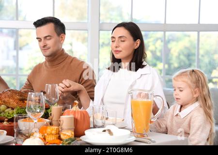 Famille heureuse priant avant le dîner à la table de fête le jour de Thanksgiving Banque D'Images