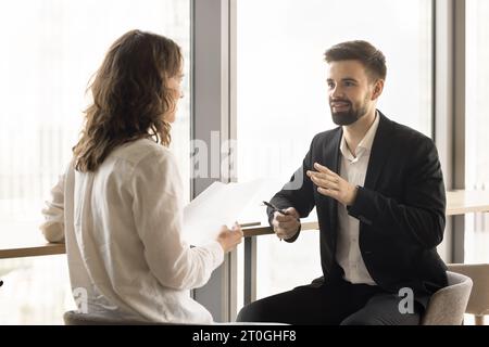 Jeunes collègues professionnels positifs discutant des rapports de projet Banque D'Images
