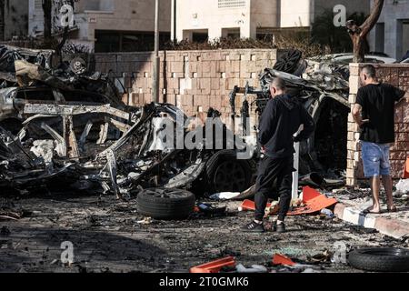 Ashkelon, Israël. 07 octobre 2023. Les résidents regardent les débris de véhicules détruits à la suite d’une attaque à la roquette depuis Gaza. Des militants palestiniens à Gaza ont tiré de manière inattendue des dizaines de roquettes sur des cibles israéliennes tôt samedi, a déclaré l’armée israélienne. Crédit : Ilia Yefimovich/dpa/Alamy Live News Banque D'Images