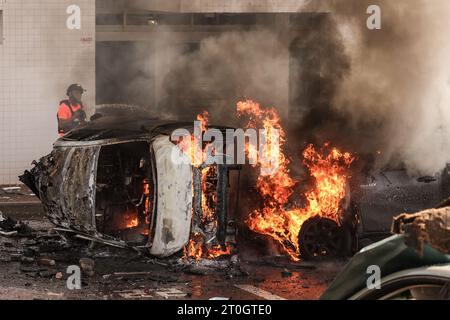 Ashkelon, Israël. 07 octobre 2023. Les gens tentent d'éteindre le feu sur les voitures après une attaque à la roquette depuis Gaza. Des militants palestiniens à Gaza ont tiré de manière inattendue des dizaines de roquettes sur des cibles israéliennes tôt samedi, a déclaré l’armée israélienne. Crédit : Ilia Yefimovich/dpa/Alamy Live News Banque D'Images
