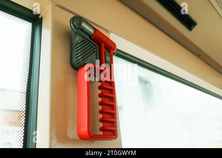 Un disjoncteur de fenêtre en verre de couleur rouge près d'une fenêtre cassable à l'intérieur d'un autobus. Il est utilisé pour briser la fenêtre en situation d'urgence. Banque D'Images