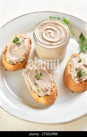 Foie de poulet pâté sur du pain grillé sur la plaque sur fond clair. Gros plan Banque D'Images