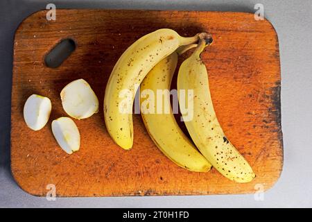 bouquet de bananes avec des tranches de pomme sur une planche à découper en bois sur un fond gris. aplatissement Banque D'Images