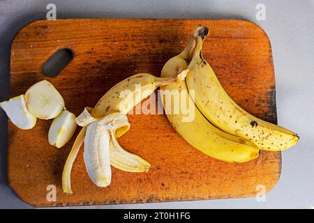 bouquet de bananes avec des tranches de pomme sur une planche à découper en bois sur un fond gris. aplatissement Banque D'Images