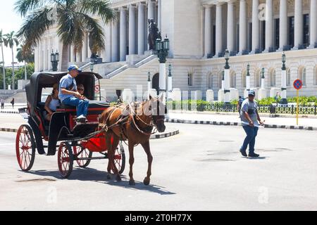 La Havane, Cuba - 29 septembre 2023 : une calèche tire sur l'extérieur du bâtiment El Capitolio. Des Cubains dans la scène Banque D'Images