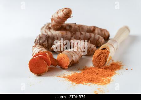 Racine de curcuma frais et curcuma moulu sur une cuillère en bois isolé sur fond blanc et espace de copie Banque D'Images