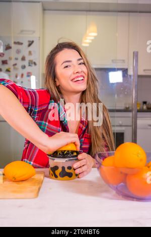 Mode de vie sain, portrait d'une jolie femme caucasienne blonde pressant des oranges faisant un jus d'orange frais Banque D'Images