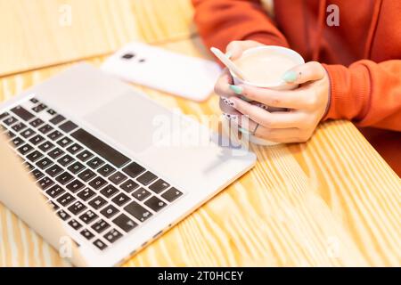 Autre personne méconnaissable avec un café chaud surfant sur Internet sur l'ordinateur Banque D'Images