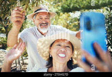 Couple senior, appel vidéo et extérieur dans le jardin, bonjour et sourire au soleil, arbres et parler sur le web. Femme mature, homme âgé et contact Banque D'Images