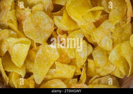 Croustilles de pommes de terre dorées dans un bol en bois - snack tentant et Crunchy fond fermé. Chips gros plan Banque D'Images