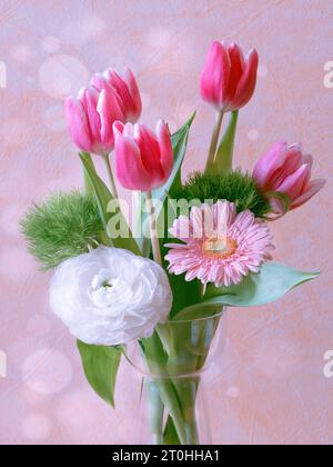 Un petit vase en céramique blanche contenant un bouquet vibrant et coloré de fleurs roses et vertes et de feuillage Banque D'Images