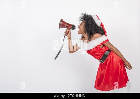 femme africaine en costume de noël criant à travers un mégaphone, fond blanc Banque D'Images