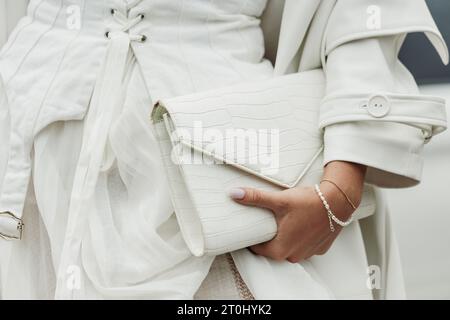 Un invité porte une robe, un manteau et un sac blancs, vus à l'extérieur du salon PRADA pendant la semaine de la mode de Milan vêtements pour femmes Printemps/été 2024. Banque D'Images