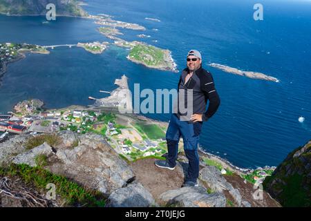 Le randonneur heureux détendu bénéficie d'une vue imprenable sur les sommets de Reinebringen des îles Lofoten, fjords, Norvège Banque D'Images