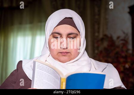 Femme musulmane portant le livre de lecture du hijab Banque D'Images