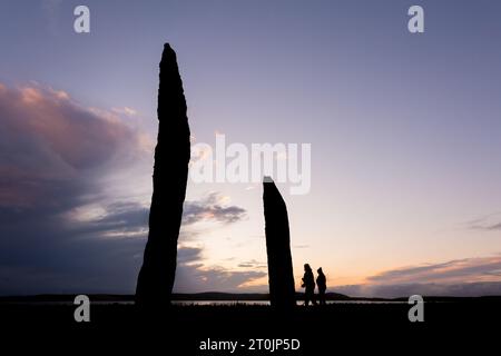 Stenness, Orcades, Royaume-Uni. 7 octobre 2023. Deux touristes visitent les magnifiques Standing Stones of Stenness au coucher du soleil, dans les Orcades, Royaume-Uni. Les énormes pierres de Stenness sont tout ce qui reste d'un grand cercle de pierres sur un ancien site cérémoniel qui date de 5000 ans. Crédit : Peter Lopeman/Alamy Live News Banque D'Images