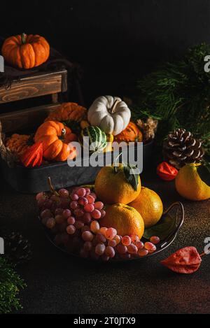 nature morte avec des raisins de citrouilles et des mandarines sur fond sombre. Photo de haute qualité Banque D'Images