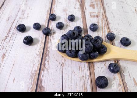 Les bleuets fraîchement cueillis dans le bol en bois. Bleuets frais et juteux avec des feuilles vertes sur la table rustique. La myrtille sur fond de bois. Ant de bleuets Banque D'Images