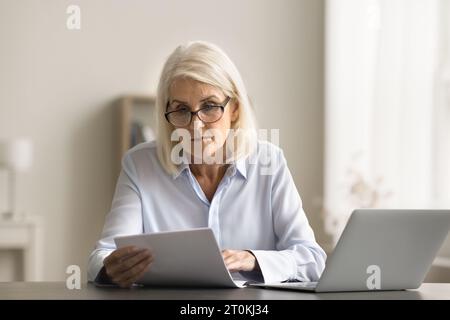 Document de lecture de femme experte en affaires senior focalisée dans les lunettes Banque D'Images