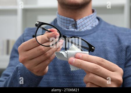 Homme essuyant les lunettes avec un chiffon en microfibre à l'intérieur, gros plan Banque D'Images