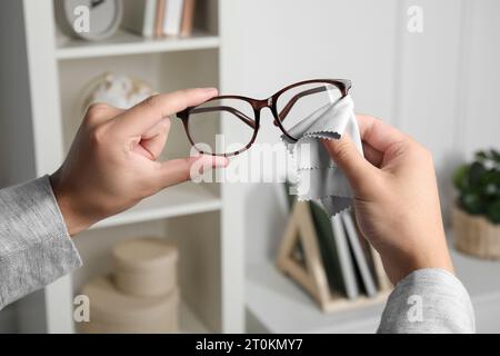 Homme essuyant les lunettes avec un chiffon en microfibre à l'intérieur, gros plan Banque D'Images