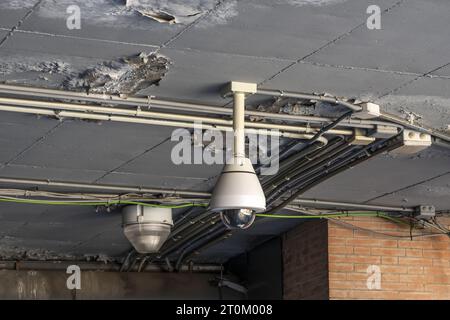 Caméra de surveillance suspendue au plafond dans une zone avec de la peinture écaillée Banque D'Images