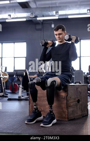 Jeune blessé ambitieux actif faisant du sport récupération d'un membre perdu grâce à la technologie moderne. amour de la vie. gars fort essayant de lever des haltères Banque D'Images