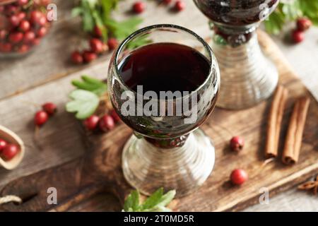 Vin médicinal préparé à partir de baies d'aubépine fraîches dans une tasse faite de soi-disant verre de forêt plein de bulles d'air Banque D'Images