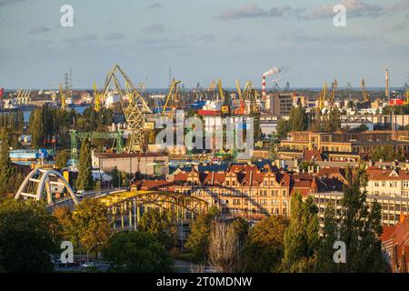 Ville de Gdansk paysage urbain industriel en Pologne, chantier naval de Gdansk avec des grues portuaires historiques emblématiques au coucher du soleil. Banque D'Images