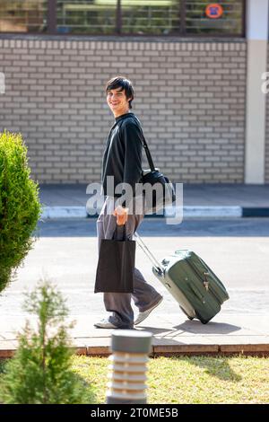 voyageur, souriant beau jeune homme portent des sacs devant l'aéroport dans la rue Banque D'Images