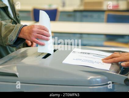 Offenbach, Allemagne. 08 octobre 2023. Un homme jette son bulletin de vote dans l'urne dans la salle de vote du centre d'éducation des adultes de Sonnemannstrasse. En Hesse, l'élection du 21e Parlement de l'État de Hesse a lieu dimanche. Crédit : Andreas Arnold/dpa/Alamy Live News Banque D'Images