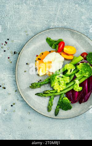 Salade de régime avec asperges, œuf poché et laitue, tomate. Banque D'Images