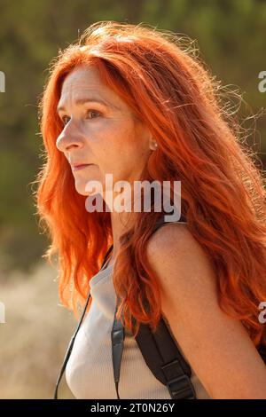 Femme mûre aux cheveux roux regardant loin dans la forêt d'Arenales del sol, Espagne Banque D'Images