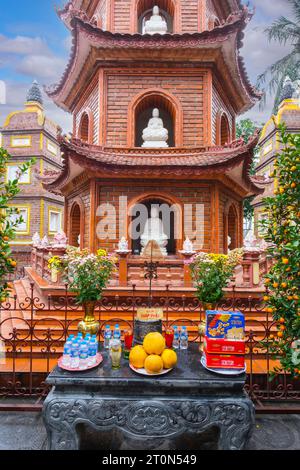 Hanoi, Vietnam. Pagode TRAN Quoc, le plus ancien temple bouddhiste de Hanoi. Bouddha dans la niche de la pagode, offrandes sur la table.. Banque D'Images