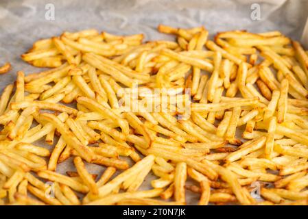 frites frites couchées sur du papier sulfurisé. Cuisson des frites surgelées au four Banque D'Images