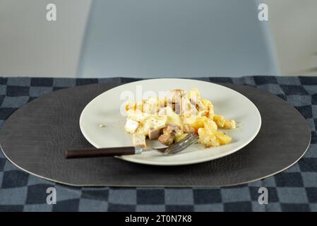 Pommes de terre sautées avec de la viande et du fromage brie sur une assiette à la table Banque D'Images