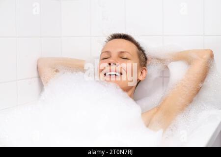 Femme mature appréciant un bain moussant apaisant Banque D'Images