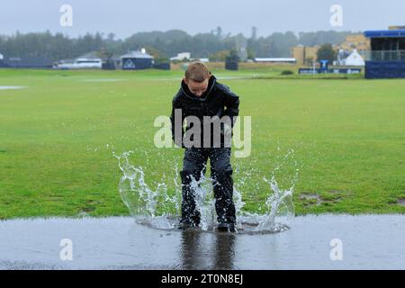 8 octobre 2023 ; Old course à St Andrews, St Andrews, Fife, Écosse ; Alfred Dunhill Links Championship, Third Round; un jeune garçon saute dans l'eau sur une Grannie Clarks Wynd inondée sur le Old course, St Andrews alors que la troisième manche du Alfred Dunhill Links Championship est annulée pour la deuxième journée consécutive en raison de fortes pluies et de l'eau stagnante sur le parcours Banque D'Images