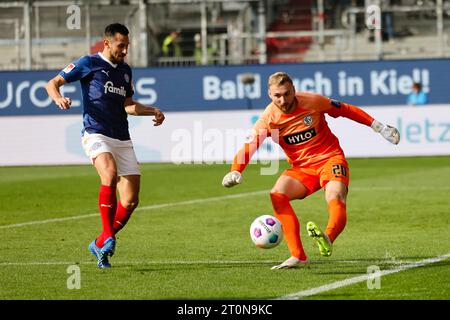 08 octobre 2023, Schleswig-Holstein, Kiel : football : 2e Bundesliga, Holstein Kiel - SV Elversberg, Journée 9, Holstein Stadium. Steven Skrzybski (à gauche) de Kiel et le gardien d'Elversberg Nicolas Kristof se battent pour le ballon. Photo : Frank Molter/dpa - REMARQUE IMPORTANTE : conformément aux exigences du DFL Deutsche Fußball Liga et du DFB Deutscher Fußball-Bund, il est interdit d'utiliser ou de faire utiliser des photographies prises dans le stade et/ou le match sous forme de séquences et/ou de séries de photos de type vidéo. Banque D'Images