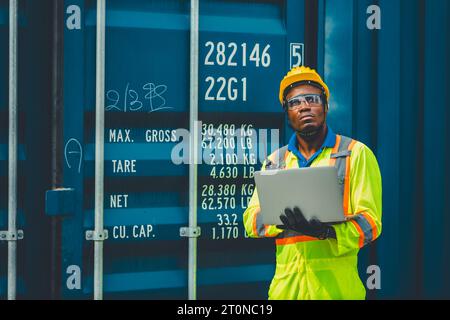 Le docker masculin africain contrôle le chargement de la cargaison de conteneurs au chantier naval de conteneurs d'entrepôt. Employé du personnel maritime et du transporteur. opérateur de chargement de cargaison s Banque D'Images