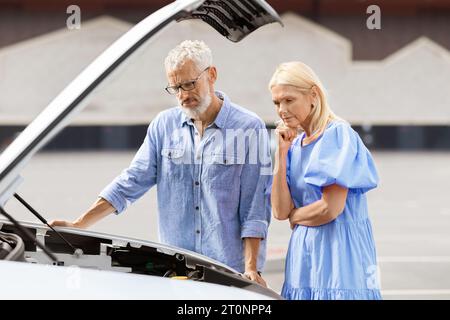 Couple senior contrarié en voyage sur la route éprouvent des problèmes, moteur en panne Banque D'Images