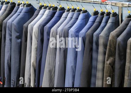 Racks avec différents costumes pour hommes dans une boutique de vêtements pour hommes. Banque D'Images