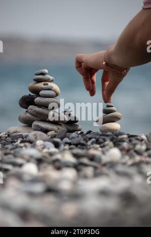 la main d'une femme empilant des cailloux les uns sur les autres sur une plage Banque D'Images