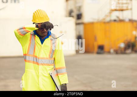 Stress fatigué épuisé travailleur sueur dans la journée chaude en été travaillant à l'extérieur dans le chantier de contrainer d'expédition de port, les gens de race noire africaine. Banque D'Images