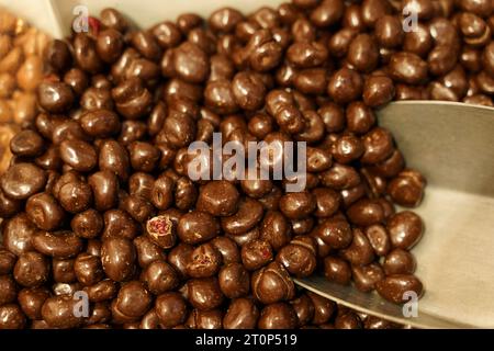 Il y a des bonbons sur le comptoir - des canneberges recouvertes de chocolat et une cuillère. Magasin de bonbons. Banque D'Images