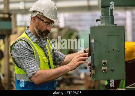 Le travail de travailleur expert masculin d'ingénieur hispanique senior opère la fraiseuse de tour de métal dans l'usine d'industrie lourde Banque D'Images