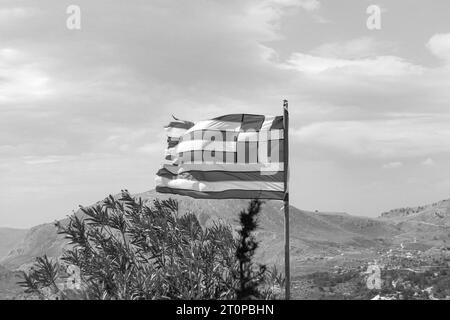 Drapeau national de la Grèce au sommet la colline du monastère de Tsambika à Rhodes, Grèce en noir et blanc Banque D'Images