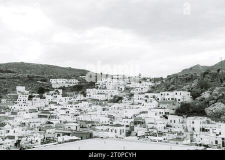 Vue en noir et blanc de la ville de Lindos, bâtiments blancs de l'Acropole de la forteresse de Lindos au sommet d'une montagne Banque D'Images