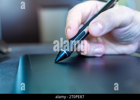 personne blanche tenant un stylet sur une tablette graphique Banque D'Images