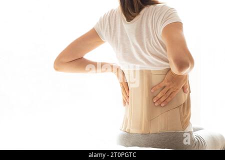 Femme avec un corset sur le dos pour soutenir son dos de la douleur dans le dos et la colonne vertébrale, concept médical, soutien spinal, mal de dos, portant une attelle à ho Banque D'Images